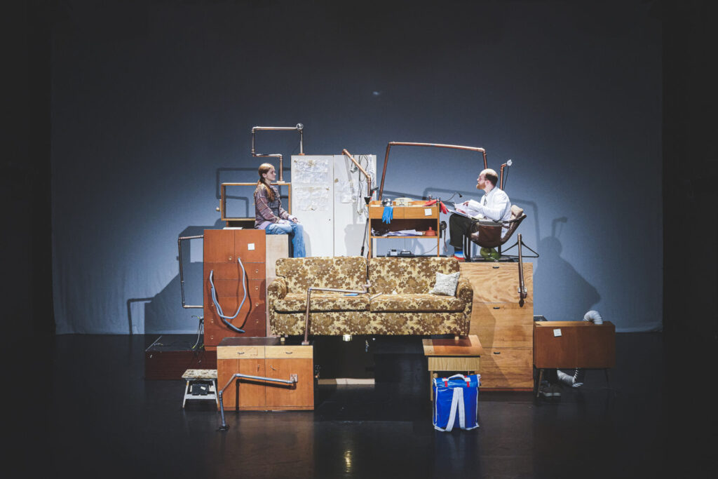 © Foto: Vanja Pandurevic Mädchen und Mann in wohnungsartigen Konstruktion mit Couch und Kästen.
