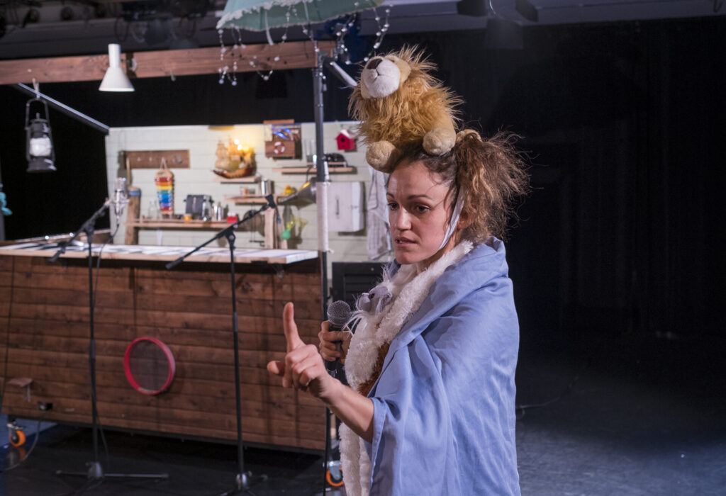 © Foto: Rainer Berson Frau mit Plüschtier auf dem Kopf hält mahnend den Zeigefinger hoch.