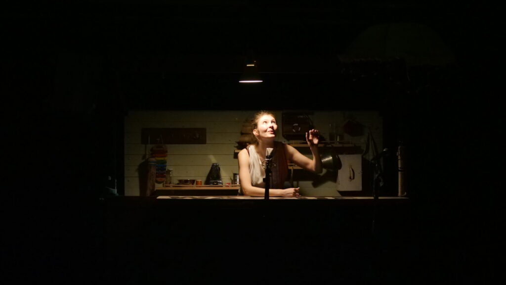 © Frau im Dunkeln blickt nach oben in den Lichtschein. Foto: Richard Schmetterer