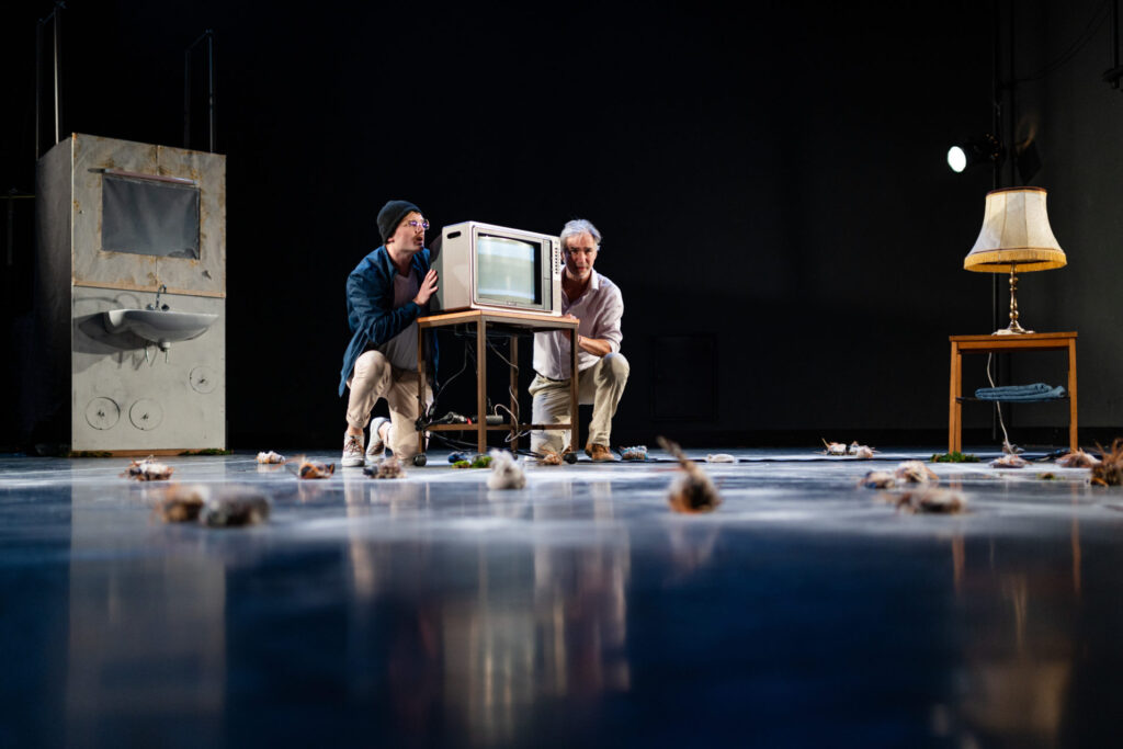 © Foto: Karin Gruber Zwei Männer verstecken sich hinter Fernseher.