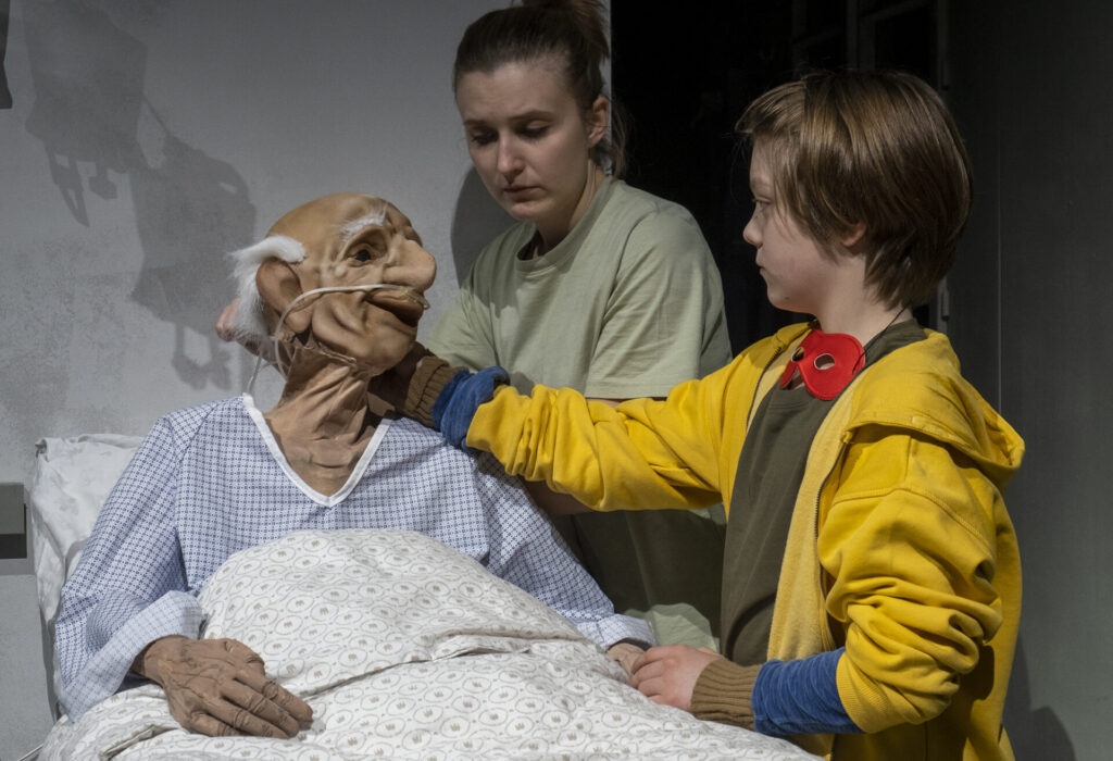 © Foto: Rainer Berson Junge sieht die Puppe eines alten Mannes neugierig an.