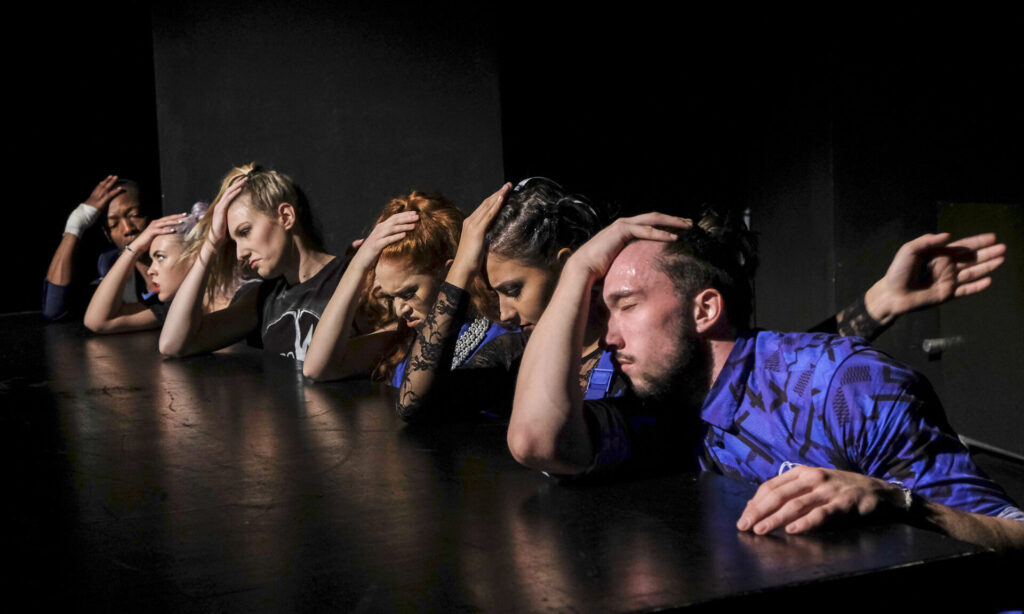 © Foto: Rainer Berson Sechs Performer:innen greifen sich gleichzeitig ungläubig auf den Kopf