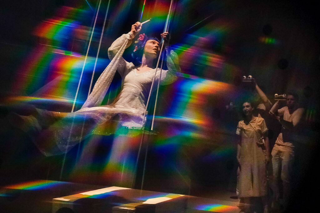 © Foto: Rainer Berson Frau in langem Kleid sitzt auf Schaukel, darüber liegt ein Schimmereffekt.